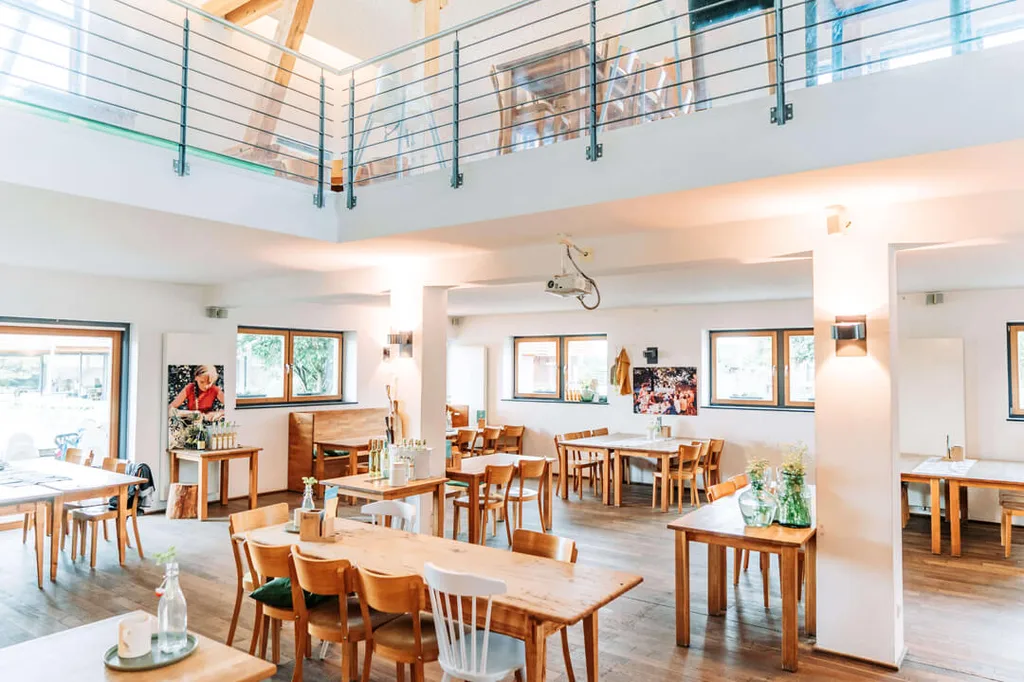 Sală luminoasă de restaurant, cu mese din lemn, la Gut Hügle