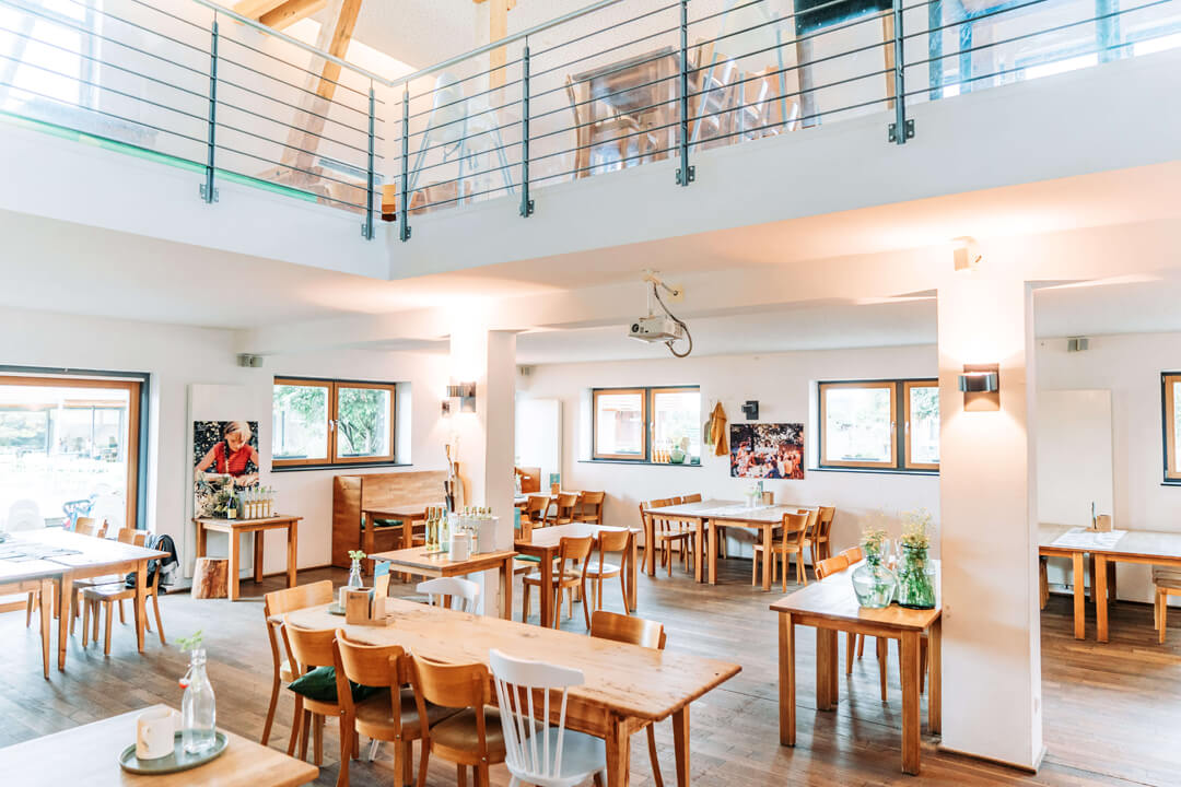 Sală luminoasă de restaurant, cu mese din lemn, la Gut Hügle